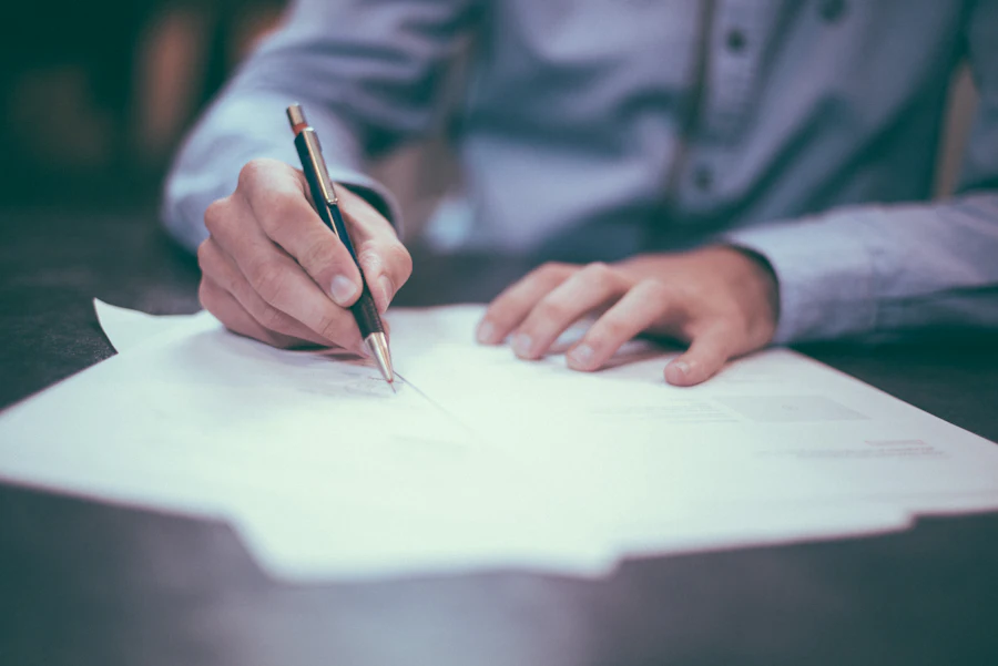 Hand signing a written service agreement on a desk