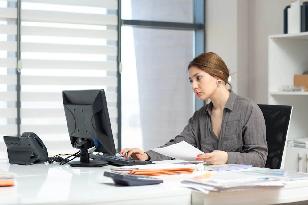 Administrator working through paperwork and invoices at an office desk