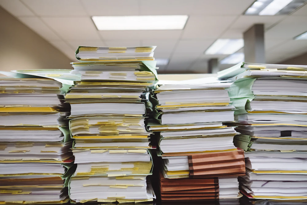 Stacked paper documents and labelled file folders in an office